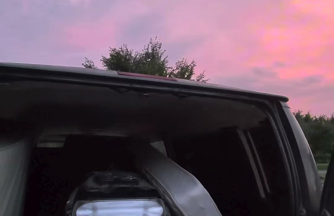 The open back of the van at dusk under a pink evening sky, the last load of the day going in.
